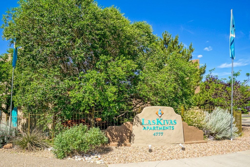 A sign for Laskinas Apartments stands in front of a green tree.